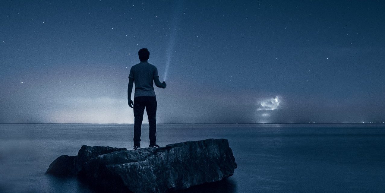 person standing on beach with flashlight