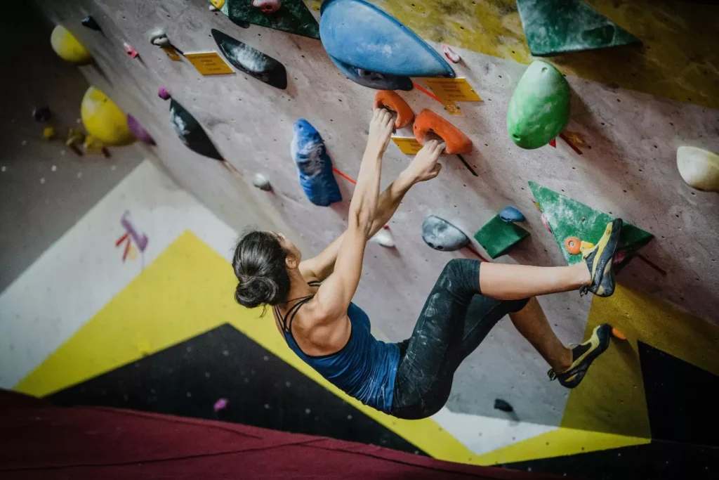 a woman finding her strength, on a climbing/bouldering wall