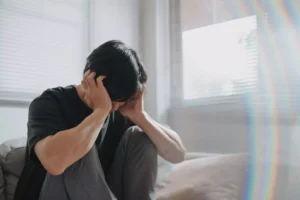 a man with depression sitting on the ground with his head in his hands