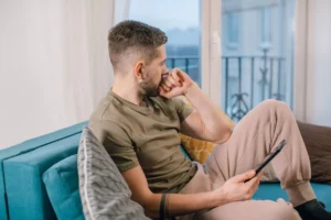 a single guy sitting on a couch looking out a window