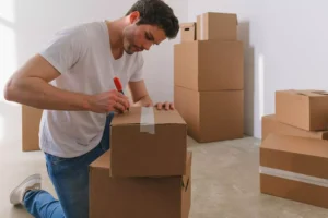 a guy labeling moving boxes, preparing for his move to a new city