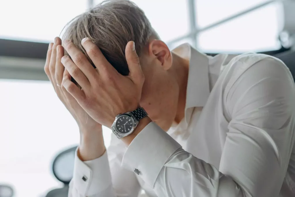 a man, feeling shame, with his head in his hands