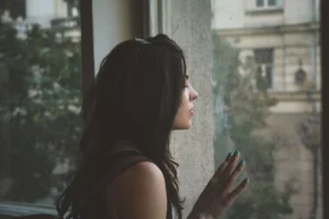 a woman looking out a window, feeling unlovable