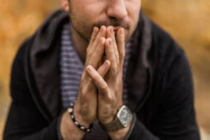 a man with his hands in front of his face, thinking, decision making