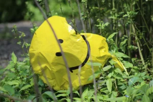 a deflated smiley face balloon in grass representing low self-esteem