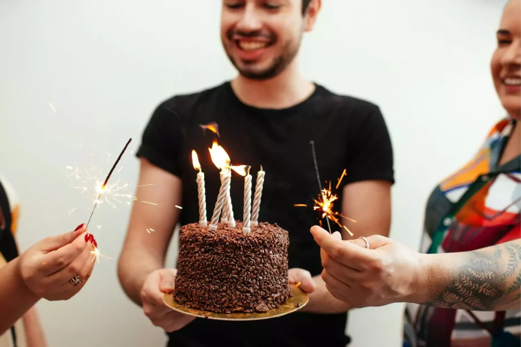a man holding a birthday cake; aging another year
