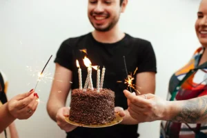 a man holding a birthday cake; aging another year