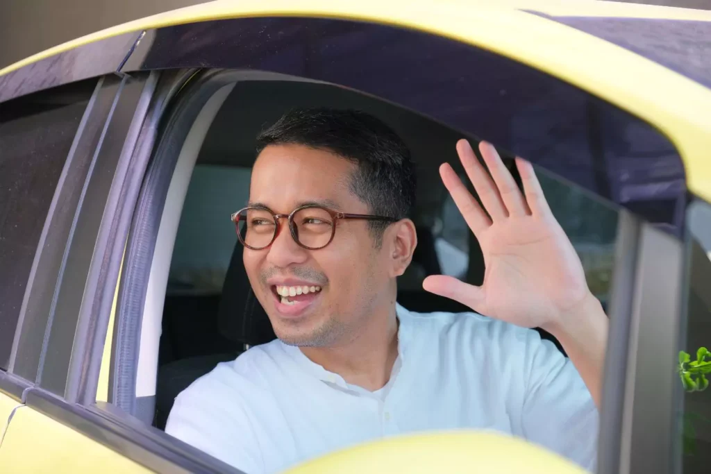 a man trying to make friends by waving to a neighbor from his car