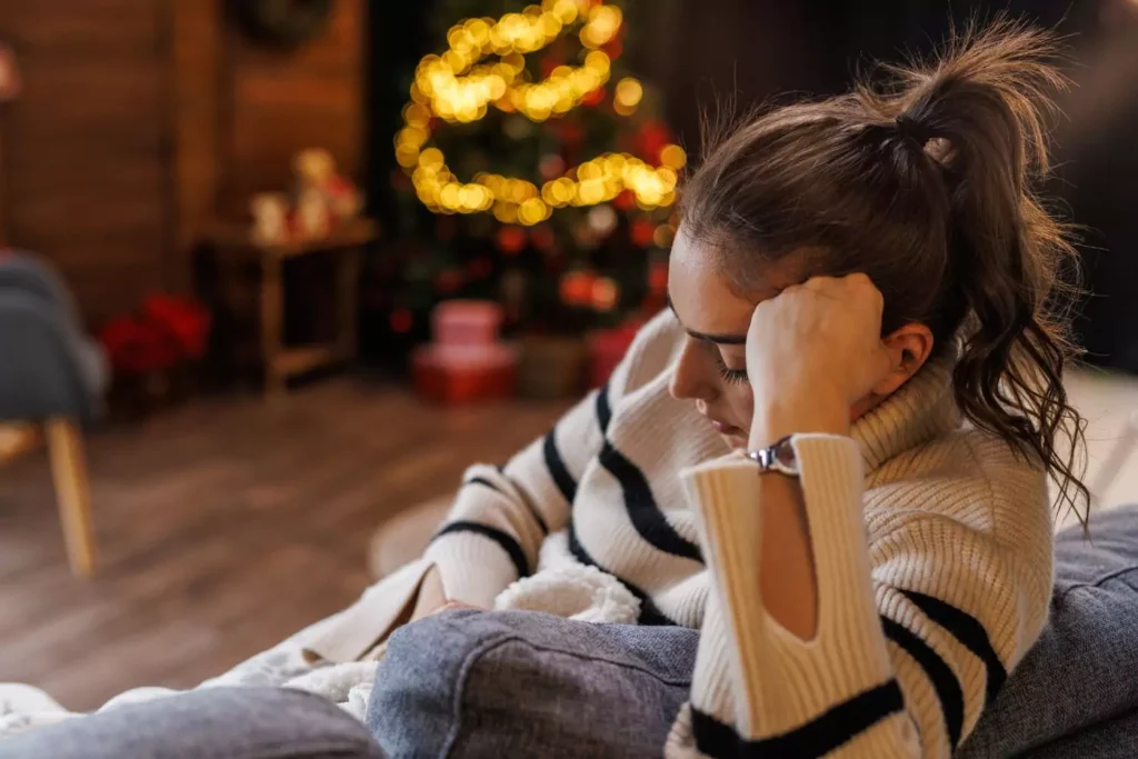 a woman sitting on her couch having a miserable holiday