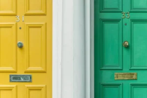an image of a yellow apartment door next to a green apartment door - neighbors