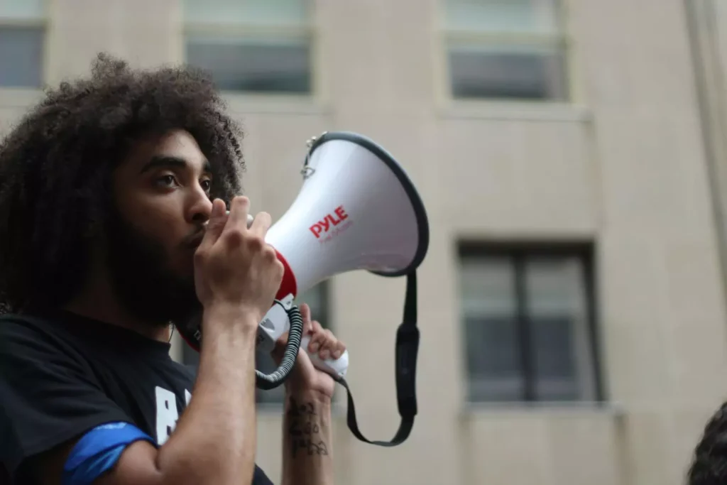 a man holding a megaphone, talking about politics