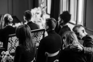 a man offering a woman empathy at a funeral by putting his hand on her shoulder