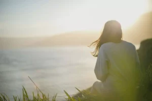 a woman sitting by the water, praying the lorica of St. Patrick