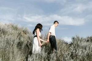 What does the Bible say about dating? Image: a couple walking in a meadow, holding hands