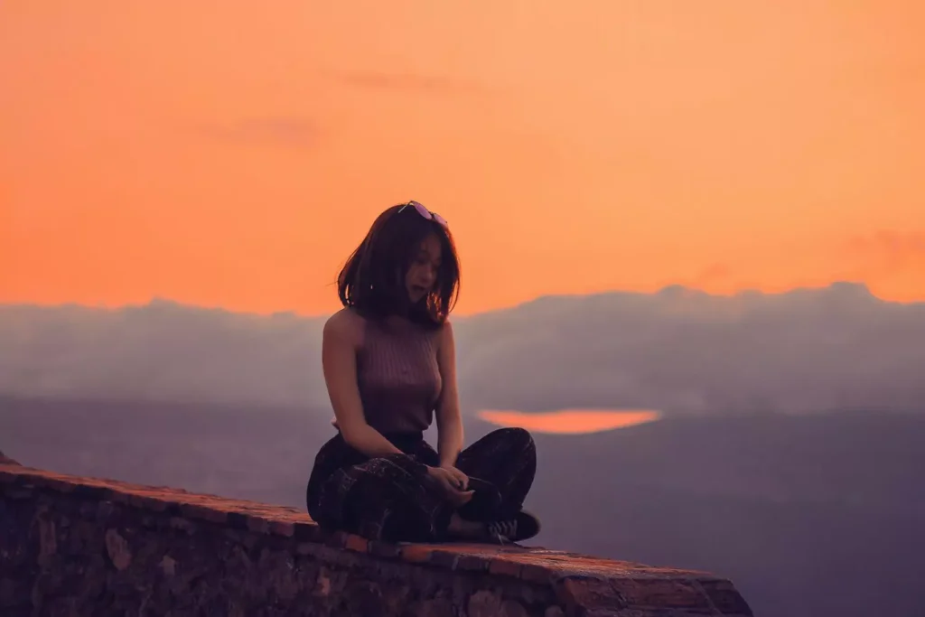 a woman finding rest on a rock during sunset