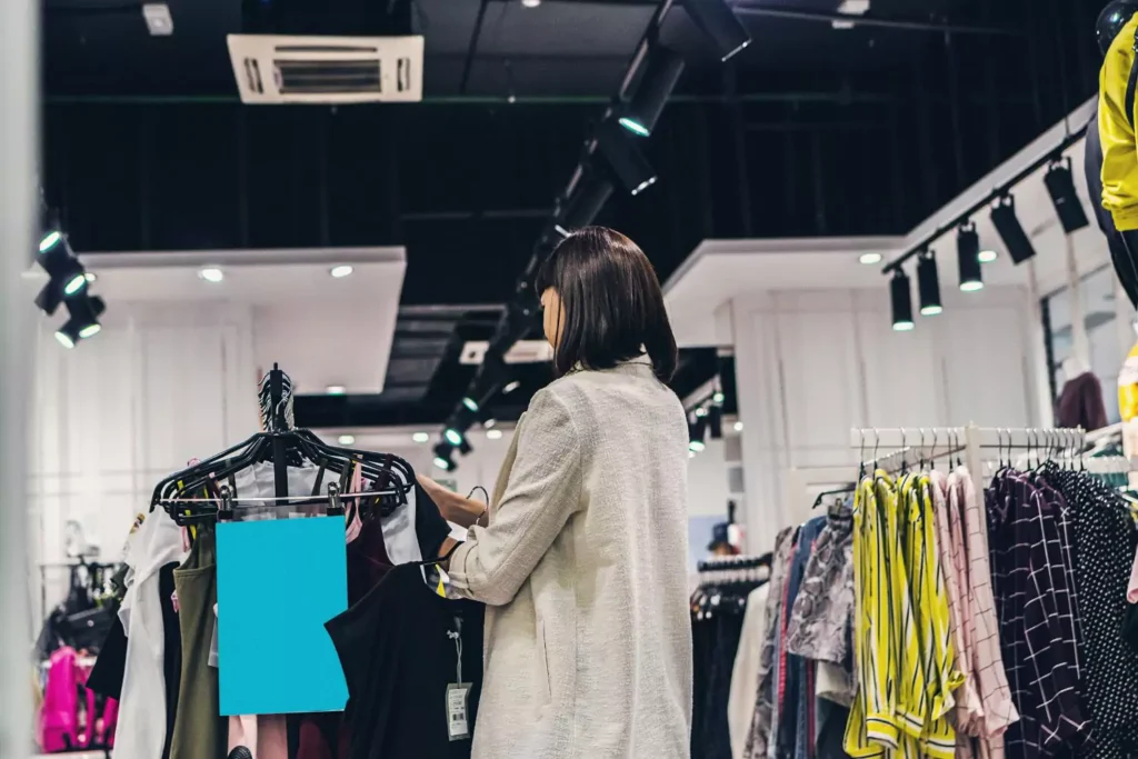 Woman browsing different styles in a clothing store.