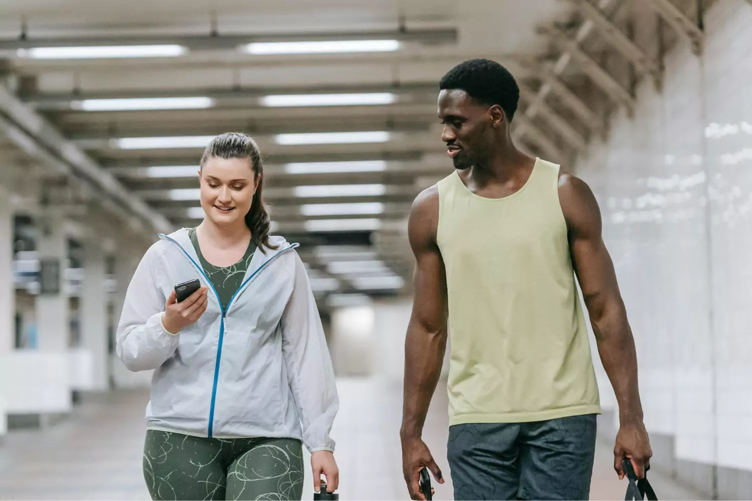 a girl looking at her phone, walking next to a guy. She needs to put her phone away